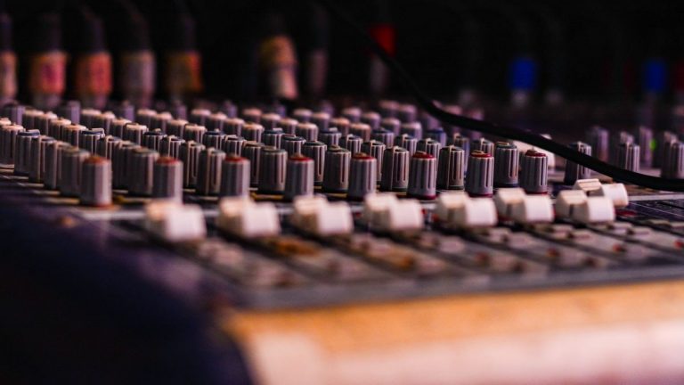 Close-up of a professional audio mixing console with knobs and sliders, essential for music production.